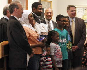 Abdul Rahim, an immigrant from Nigeria, is joined by his entire family for a picture Saturday after he was sworn in as a U.S. citizen at a naturalization ceremony at the Norman Rockwell Museum in Stockbridge. Gov. Deval Patrick is seen at rear. (Stephanie Zollshan / Berkshire Eagle Staff) 